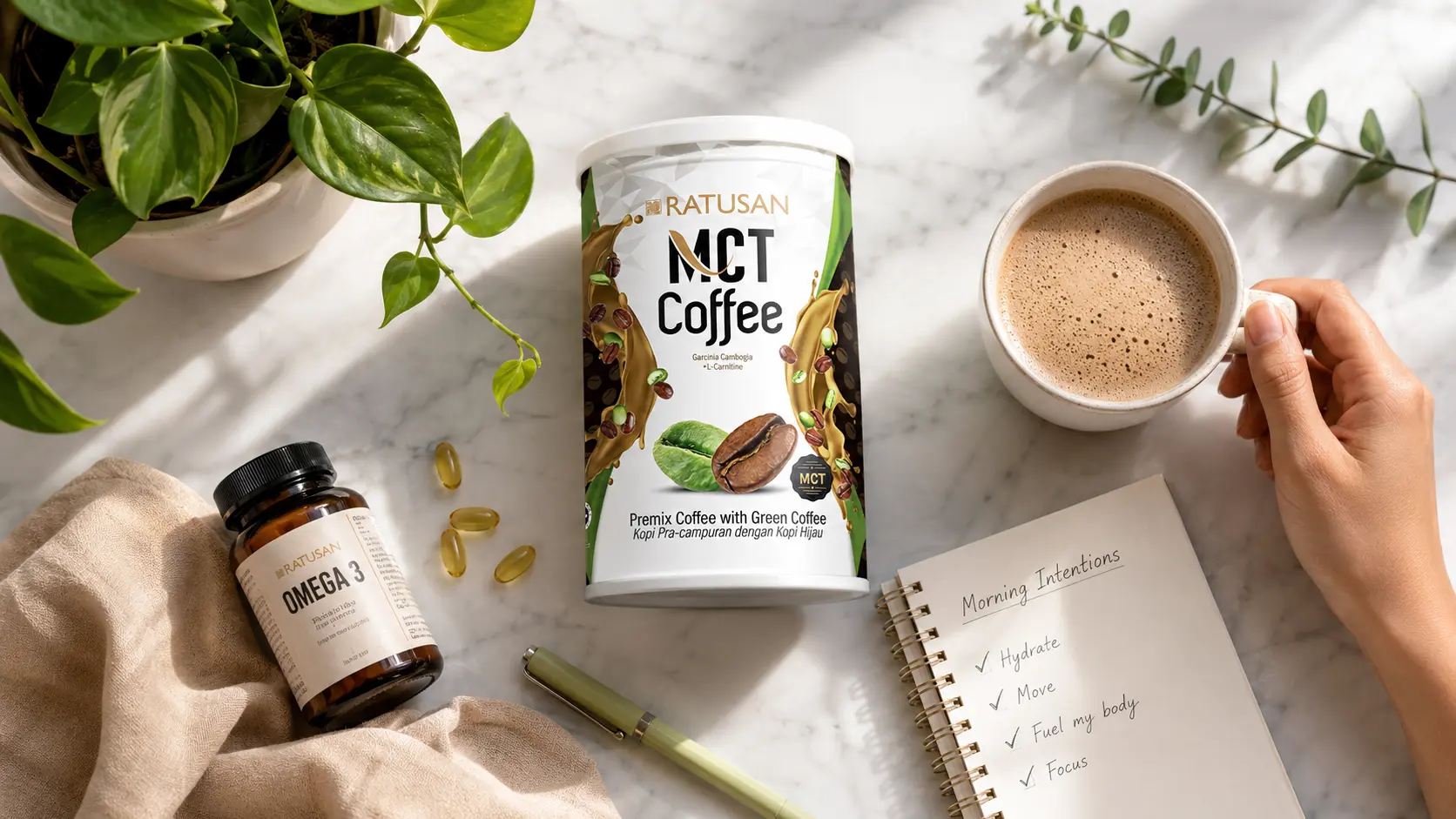 Morning wellness flat lay with MCT coffee, journal, green plants and vitamins on white marble